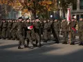 Żołnierze w mundurach stoją w szeregu. 28 listopada święto upamiętnia ważne wydarzenia. W tle drzewa i budynki.
