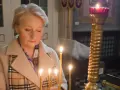 Kobieta w kościele zapala świece. To szczególny dzień, imieniny Eryka, więc modli się o jego pomyślność.
