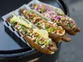 Trzy apetyczne hot dogi z różnymi dodatkami, idealne na 15 lipca nietypowe święta.