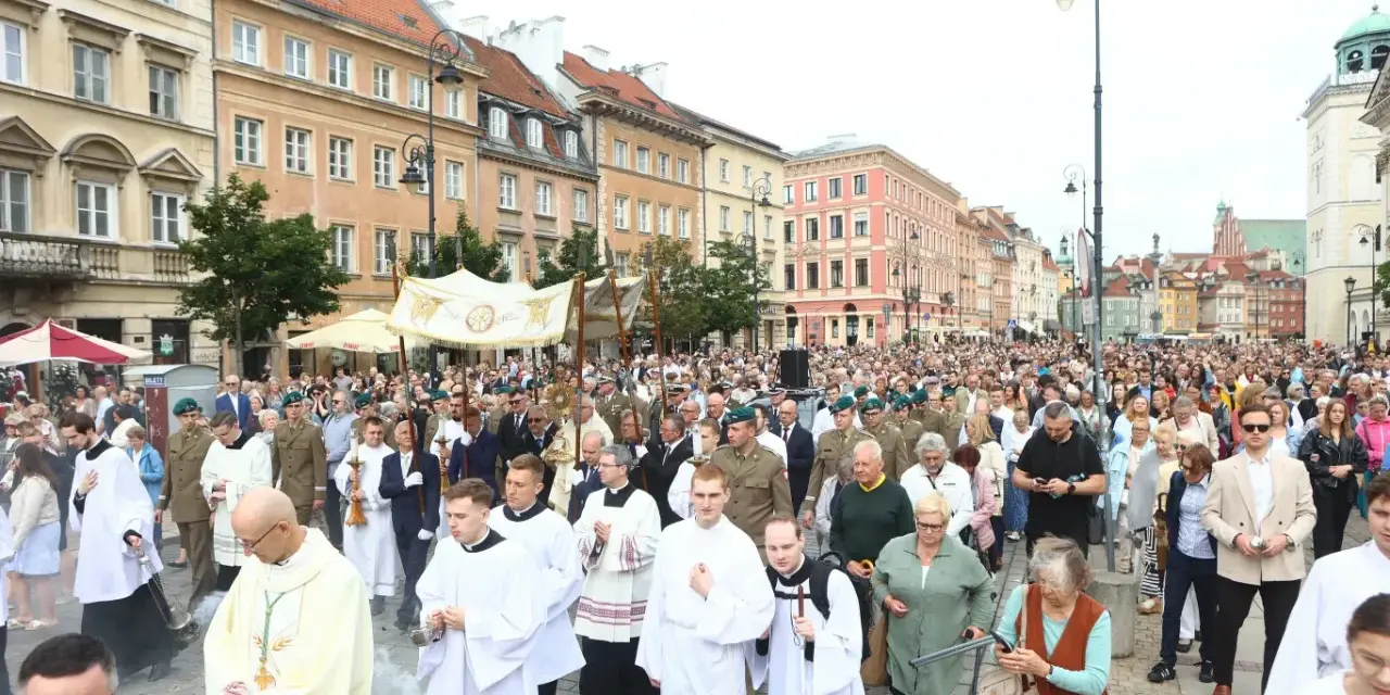 26 czerwca. Procesja z kapłanami w strojach liturgicznych i wiernymi maszeruje ulicą w otoczeniu zabytkowych kamienic.