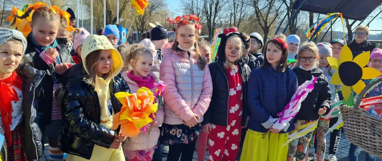 Dzieci w barwnych strojach, z kwiatami i ozdobami, świętują dzień zięcia.