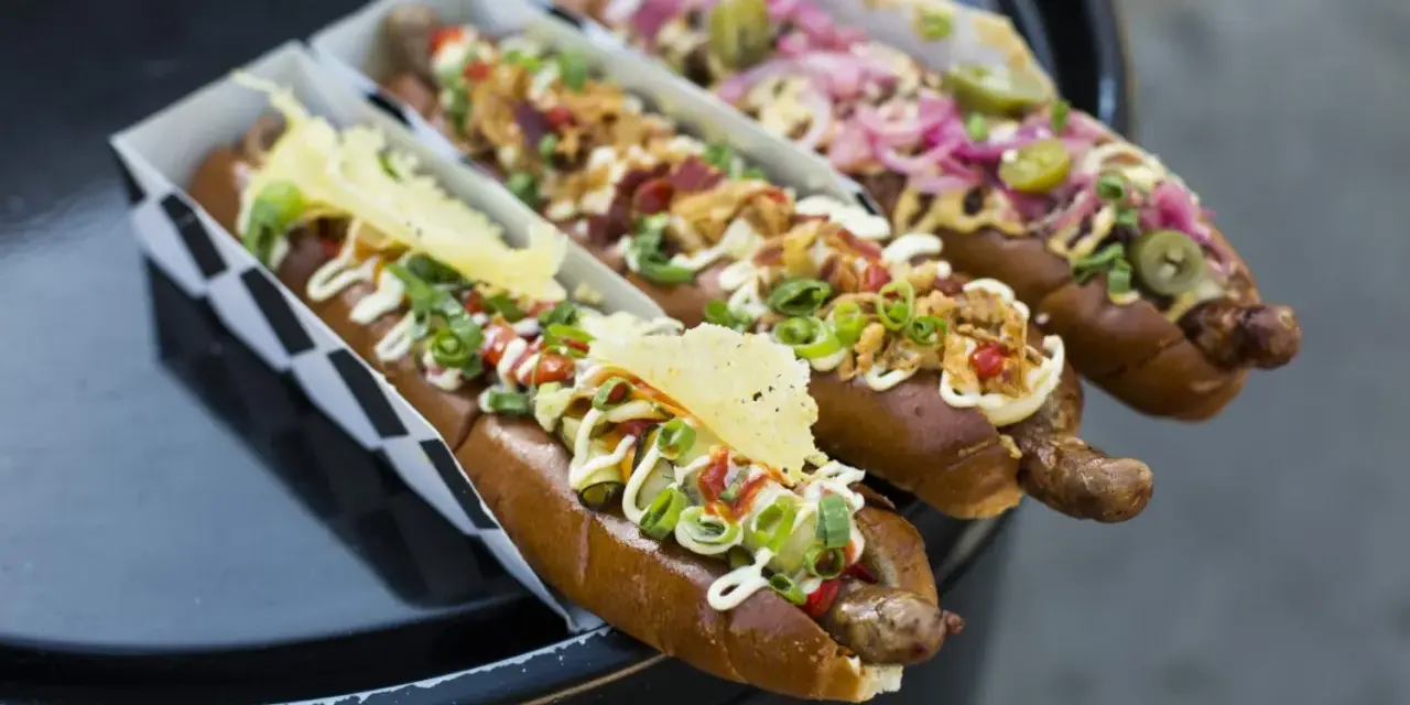 Trzy apetyczne hot dogi z różnymi dodatkami, idealne na 15 lipca nietypowe święta.