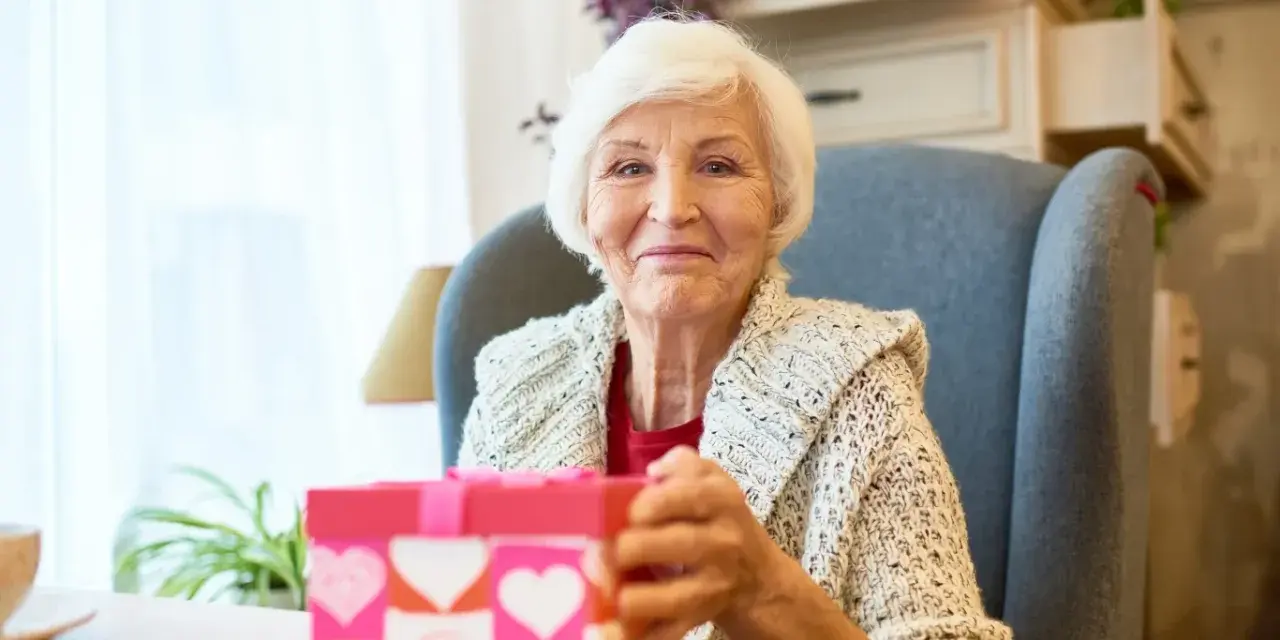 Uśmiechnięta babcia z prezentem w kształcie serca, gotowa na dzień babci 2026.