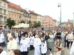 26 czerwca. Procesja z kapłanami w strojach liturgicznych i wiernymi maszeruje ulicą w otoczeniu zabytkowych kamienic.