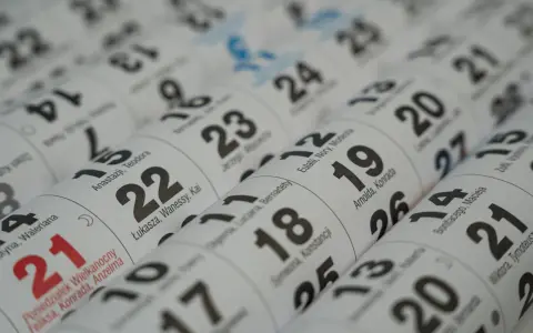 Zbliżenie na kalendarz z zaznaczonymi imieniami. Widoczne daty i imiona, np. 21, 22, 23, 24, 25, 26, 27. Może to być kalendarz na imieniny Witolda.