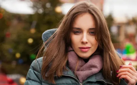 Weronika w zimowej kurtce i szaliku, z choinką w tle. Czas na świętowanie, kiedy są imieniny Weroniki!