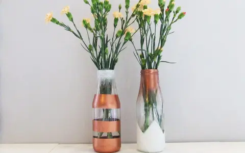 Dwa szklane wazony DIY z kwiatami. Jeden w paski miedziane, drugi z miedzianym ombre i białym dołem.