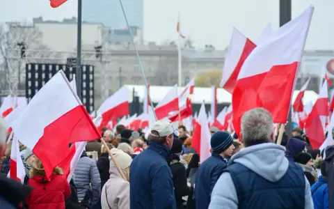 Tłum ludzi z polskimi flagami. W tle scena i budynki. Może to być związane z jakimś wydarzeniem narodowym, ale nie ma informacji, jakie święto jest 11 października.