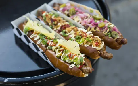 Trzy apetyczne hot dogi z różnymi dodatkami, idealne na 15 lipca nietypowe święta.