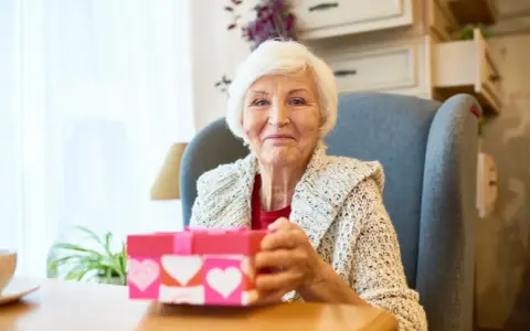 Uśmiechnięta babcia z prezentem w kształcie serca, gotowa na dzień babci 2026.