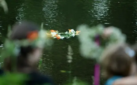 Wianek z kwiatów płynie po wodzie. 23 czerwca, w noc Kupały, ludzie wrzucają wianki do rzeki.