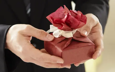 Elegancko zapakowany prezent z czerwoną różą z papieru, idealny na imieniny Włodzimierza.