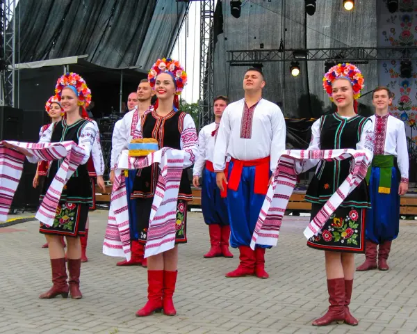 Grupa młodych ludzi w tradycyjnych strojach ludowych, świętująca imieniny Lecha. Dziewczęta w kolorowych wiankach i haftowanych sukniach, chłopcy w białych koszulach i niebieskich spodniach.