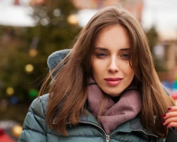 Weronika w zimowej kurtce i szaliku, z choinką w tle. Czas na świętowanie, kiedy są imieniny Weroniki!