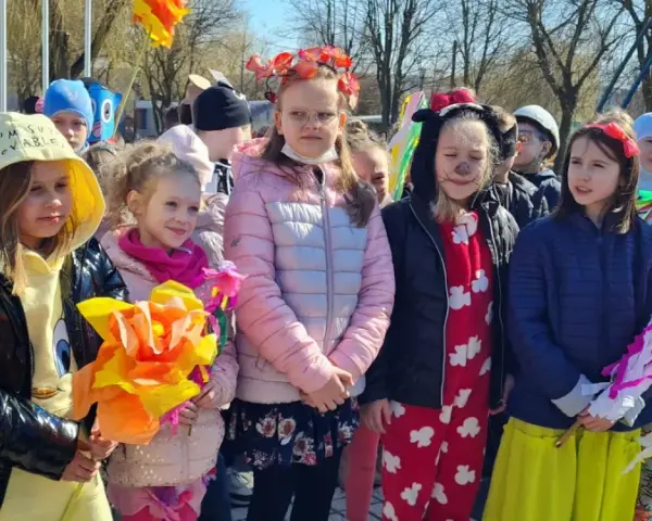 Dzieci w barwnych strojach, z kwiatami i ozdobami, świętują dzień zięcia.