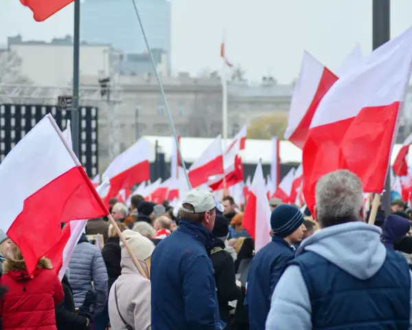 Tłum ludzi z polskimi flagami. W tle scena i budynki. Może to być związane z jakimś wydarzeniem narodowym, ale nie ma informacji, jakie święto jest 11 października.