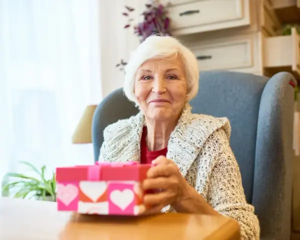Uśmiechnięta babcia z prezentem w kształcie serca, gotowa na dzień babci 2026.