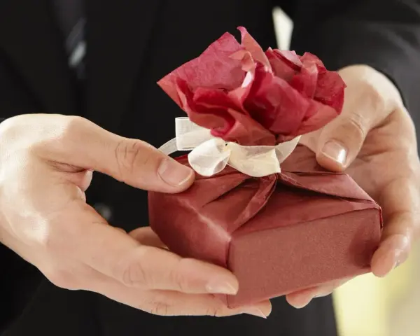 Elegancko zapakowany prezent z czerwoną różą z papieru, idealny na imieniny Włodzimierza.