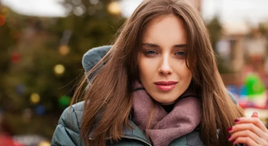 Weronika w zimowej kurtce i szaliku, z choinką w tle. Czas na świętowanie, kiedy są imieniny Weroniki!
