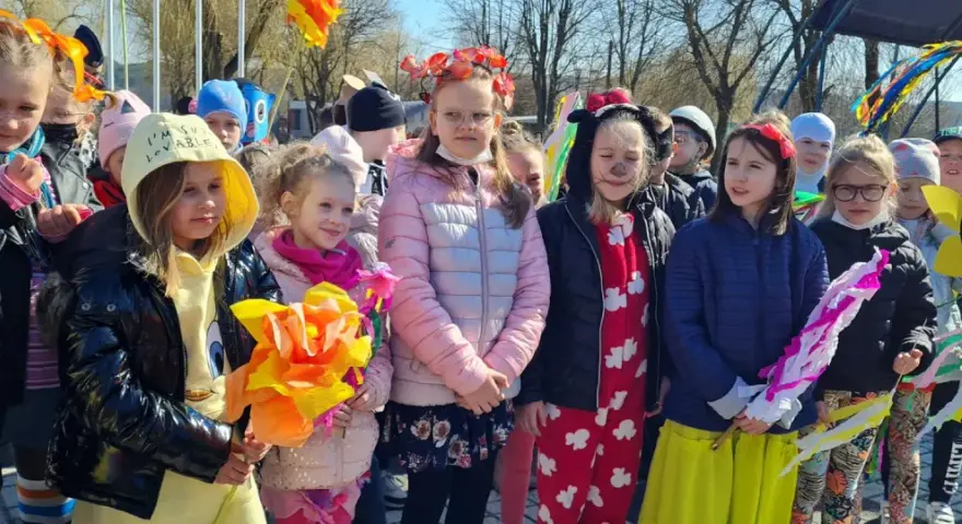Dzieci w barwnych strojach, z kwiatami i ozdobami, świętują dzień zięcia.