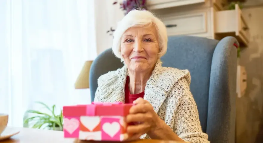 Uśmiechnięta babcia z prezentem w kształcie serca, gotowa na dzień babci 2026.