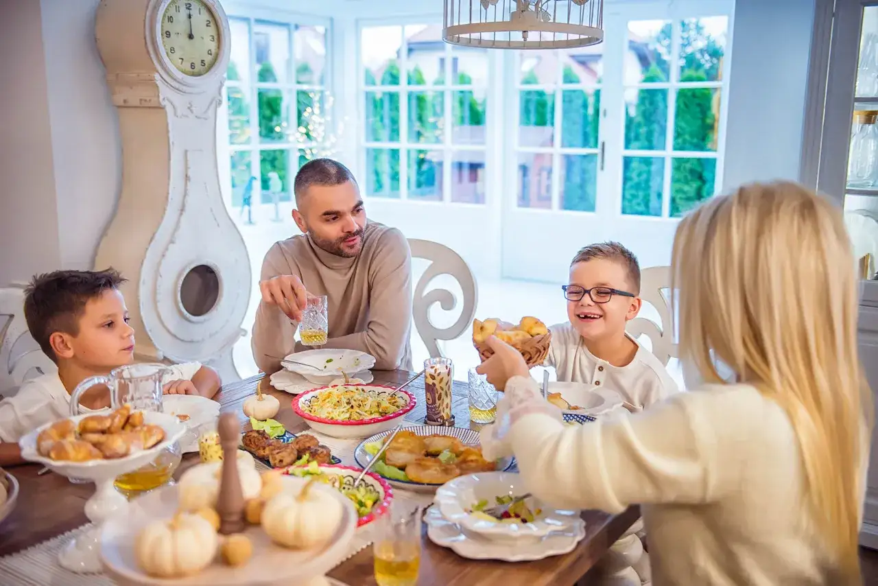 Rodzina przy stole, świętuje dzień szwagra. Dzieci jedzą, a tata wznosi toast.