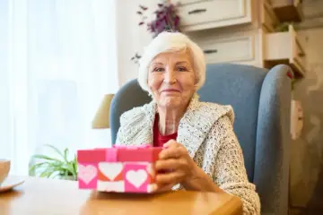 Uśmiechnięta babcia z prezentem w kształcie serca, gotowa na dzień babci 2026.